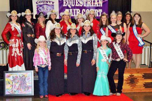 A group of young women in cowboy attire poses on stage, showcasing pageant sashes and crowns at an equestrian event.