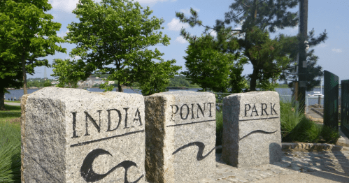 Three stone markers reading "India Point Park" with trees and a river in the background on a sunny day.