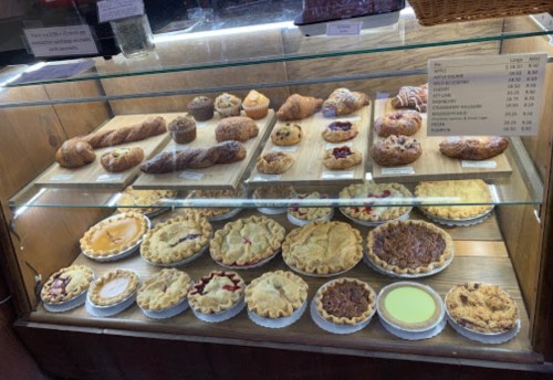 A display case filled with various baked goods, including pies, pastries, and muffins.