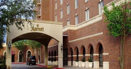 Exterior view of a Marriott hotel featuring brick architecture and a covered entrance with trees nearby.