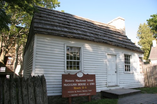 Historic McGulpin House on Mackinac Island, featuring a wooden exterior and a sign detailing visiting hours.