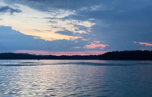 A serene lake at sunset, with soft pink and blue hues in the sky and gentle ripples on the water's surface.