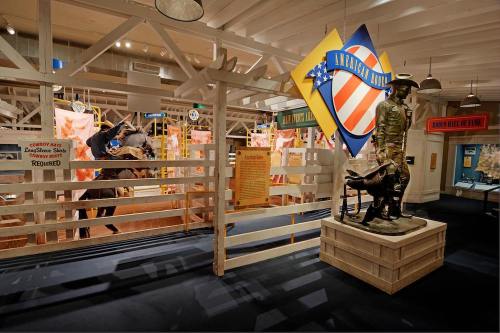 A museum exhibit featuring a statue of a cowboy with a dog, surrounded by colorful displays and signage.