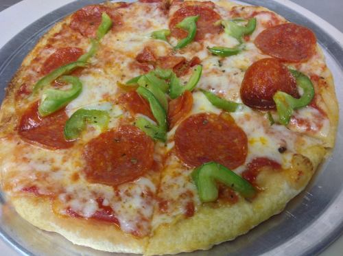 A freshly baked pizza topped with pepperoni, green bell peppers, and melted cheese on a golden crust.