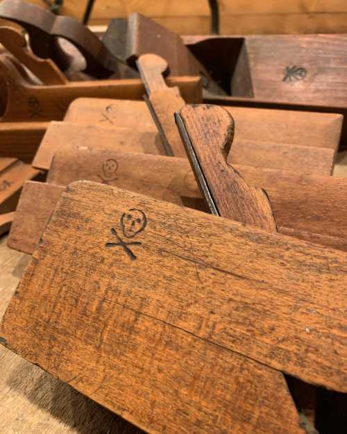 A collection of vintage wooden hand planes with carved symbols on their surfaces, arranged on a wooden table.