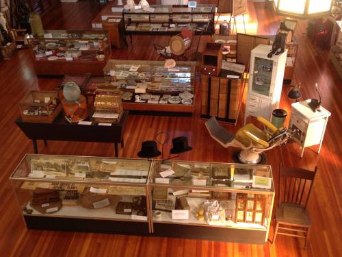 Aerial view of a museum exhibit featuring glass display cases filled with various historical artifacts and furniture.