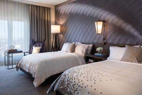 A modern hotel room featuring two beds, elegant decor, and large windows with natural light.