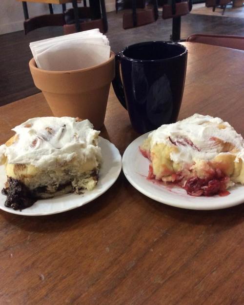 Two plates of dessert with whipped cream and fruit filling, alongside a coffee mug and a small plant pot on a wooden table.