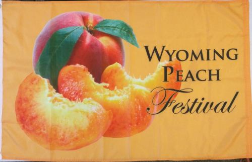 A vibrant banner featuring a peach and peach slices with the text "Wyoming Peach Festival."