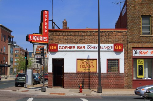 Exterior of Gopher Bar Coney Island, featuring a brick facade and neon signs, located on a city street.