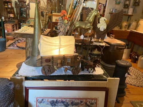 A vintage display featuring a toy wagon, decorative horse, and various antiques in a cozy shop setting.