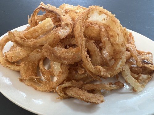A plate of crispy, golden-brown onion rings piled high.