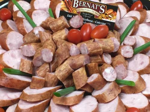 A platter of sliced sausage pieces, cherry tomatoes, and green onions, with a Bernat's label in the center.