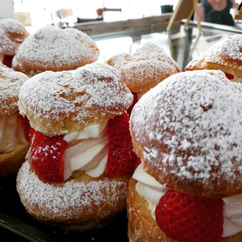 Delicious cream-filled pastries topped with strawberries and dusted with powdered sugar.