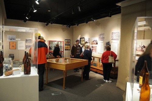 Visitors explore an exhibit in a museum, surrounded by displays and historical photographs.