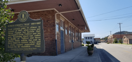 Historic marker about the Rowan County War (1864-1867) beside a brick building on a quiet street.