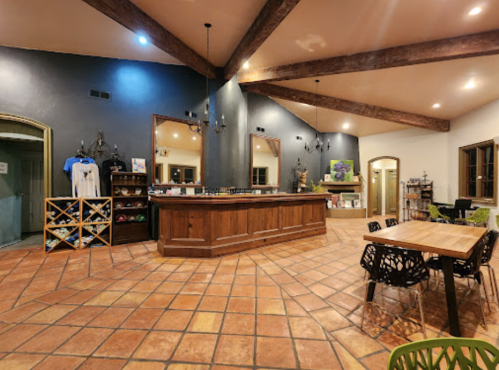A spacious interior with a wooden bar, tiled floor, and seating area, featuring warm lighting and rustic decor.