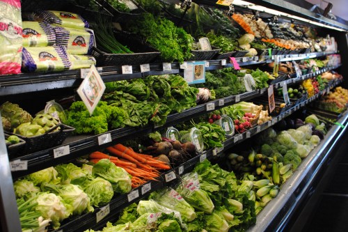 A vibrant display of fresh vegetables, including lettuce, carrots, and various greens, in a grocery store.