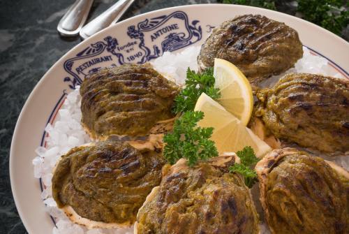 A plate of grilled oysters on ice, garnished with lemon wedges and parsley, served at a restaurant.
