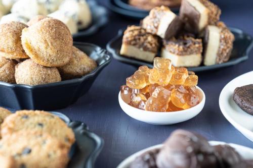 A variety of sweets including cookies, brownies, and gummy bears arranged on black and white plates.