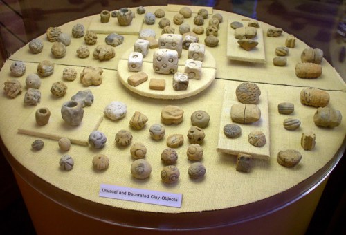A display of various unusual and decorated clay objects arranged on a circular and rectangular surface.