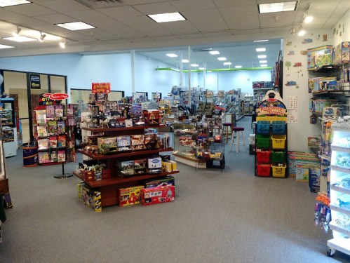 A spacious toy store filled with shelves of games, puzzles, and colorful displays. Brightly lit and inviting atmosphere.
