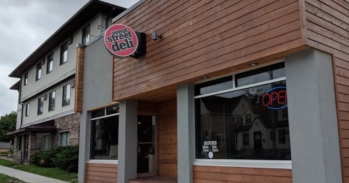Exterior of West Street Deli, featuring a wooden facade and an "OPEN" sign in the window.