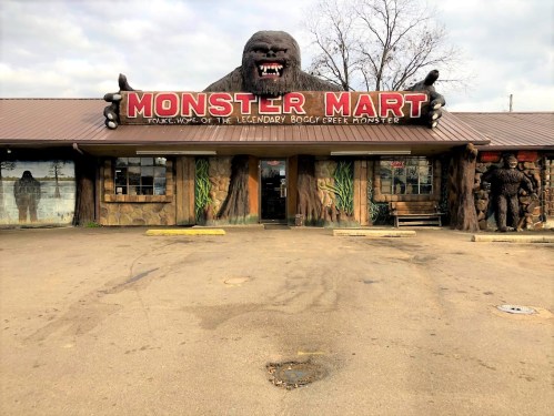 A quirky store called "Monster Mart," featuring a large gorilla statue and murals of Bigfoot on the exterior.