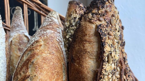 Close-up of various artisanal breads, showcasing crusty textures and a variety of seeds on the surface.