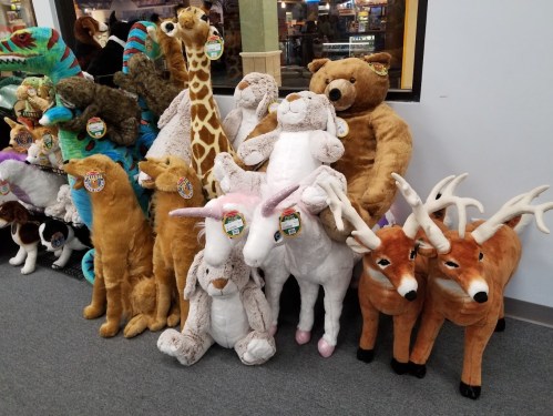 A variety of large stuffed animals, including bears, giraffes, rabbits, unicorns, and deer, displayed in a store.