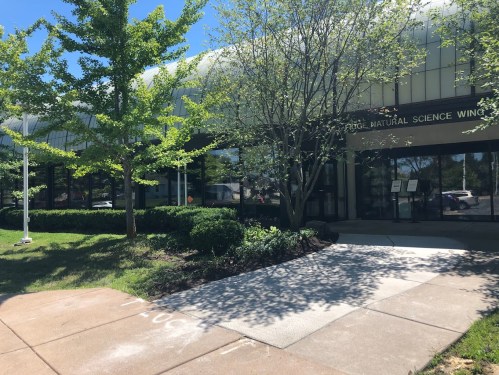 Exterior view of the Dodge Natural Science Wing, featuring greenery and a clear blue sky.