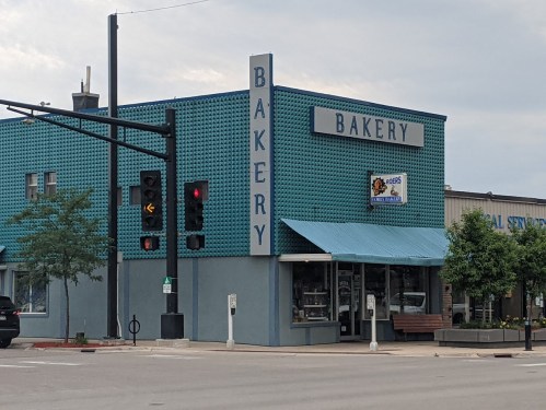 A blue bakery building with large "BAKERY" signage, located at an intersection with traffic lights.
