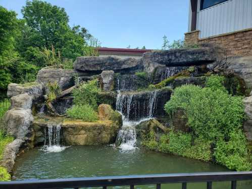 A serene waterfall cascading over rocks into a calm pond, surrounded by lush greenery and trees.