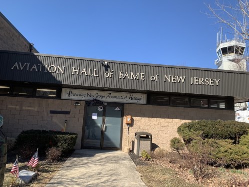 Exterior of the Aviation Hall of Fame of New Jersey, featuring a sign and a clear blue sky.