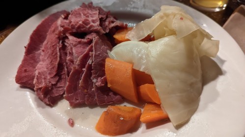 A plate with slices of corned beef, cooked carrots, and cabbage.