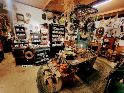 A cozy shop interior filled with shelves of jars, dried flowers, and rustic decor, creating a warm, inviting atmosphere.