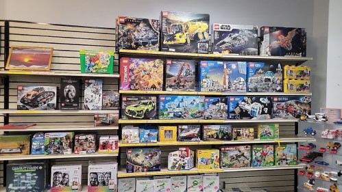 A colorful display of various LEGO sets on shelves, featuring themes like Star Wars, City, and more.