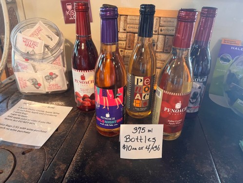 A display of five colorful wine bottles on a table, with a sign offering a deal on 375 ml bottles.