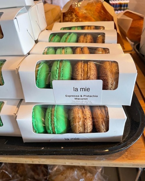 Boxes of colorful macarons in green and brown, labeled "la mie" with flavors Espresso and Pistachio.