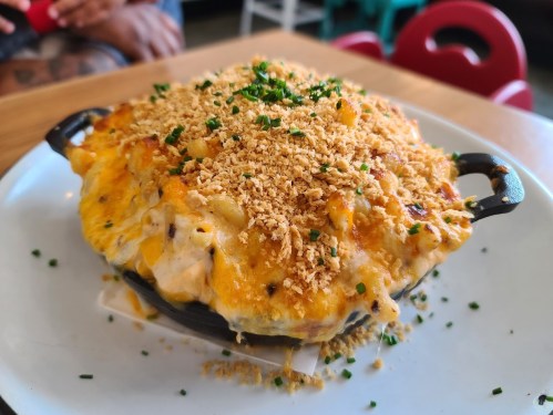 A cheesy baked macaroni dish topped with crispy breadcrumbs and fresh herbs, served in a small cast iron skillet.