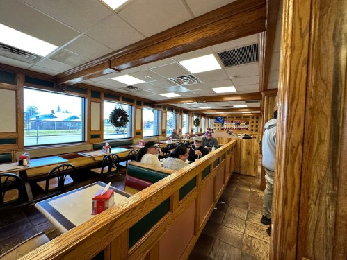 A cozy diner interior with wooden accents, featuring tables and a few patrons enjoying their meals.