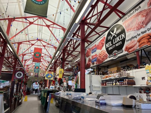 Interior of a market with colorful banners, meat displays, and festive decorations hanging from the ceiling.