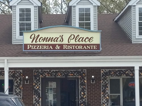 Sign for "Nonna's Place Pizzeria & Ristorante" on a building with decorative windows and an open sign.