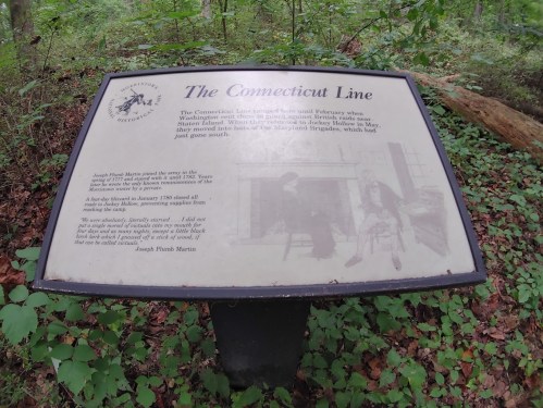 Sign about the Connecticut Line, detailing its history and significance, surrounded by greenery in a forested area.