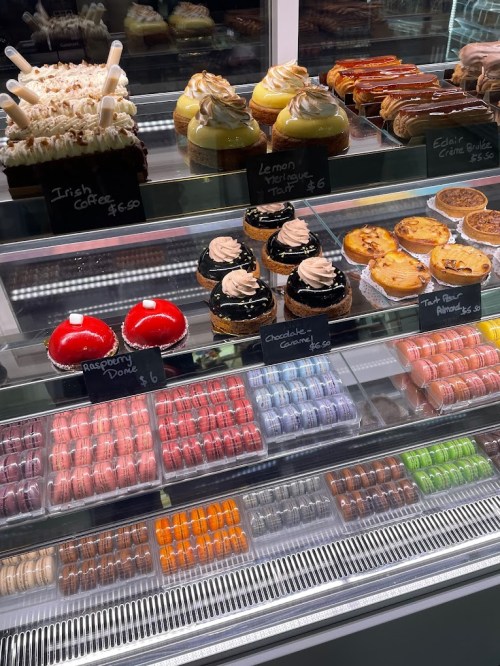 A display case filled with various desserts, including cupcakes, macarons, and pastries.