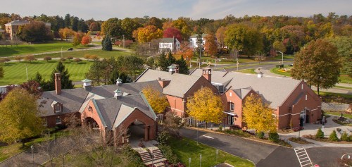 Aerial view of a brick building surrounded by colorful autumn trees and a green landscape.