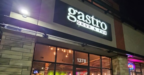 Exterior view of Gastro Grub & Pub at night, featuring a lit sign and large windows.
