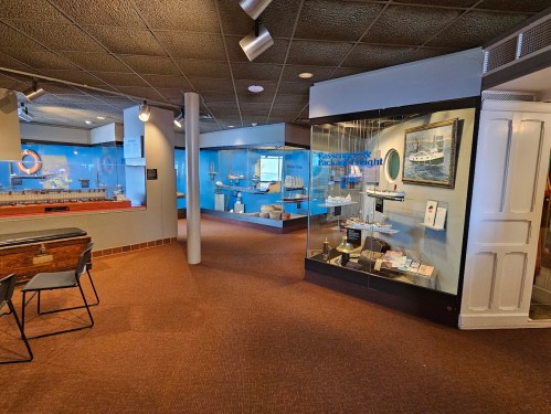 Interior view of a museum exhibit featuring model ships and maritime displays in well-lit glass cases.