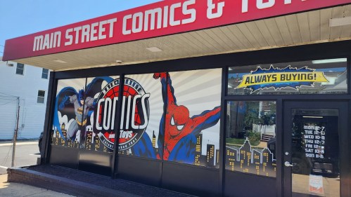 Storefront of Main Street Comics & Toys featuring superhero murals of Batman and Spider-Man, with a sign saying "Always Buying!"