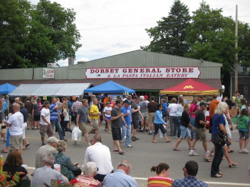A bustling street fair in Dorset, featuring food stalls and a crowd enjoying the festivities.